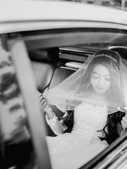 A beautiful black and white portrait of the bride in her wedding car, adjusting her veil. A quiet, contemplative moment before arriving at the church.