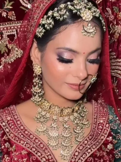 A bride in a red and green velvet lehenga, adorned with a unique chandbali-style Polki necklace. The soft makeup look lets the jewellery take center stage.