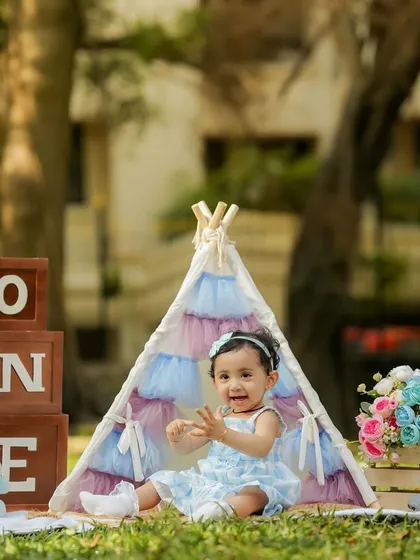 This little girl is all smiles in her pastel-colored tent during her outdoor first birthday shoot.