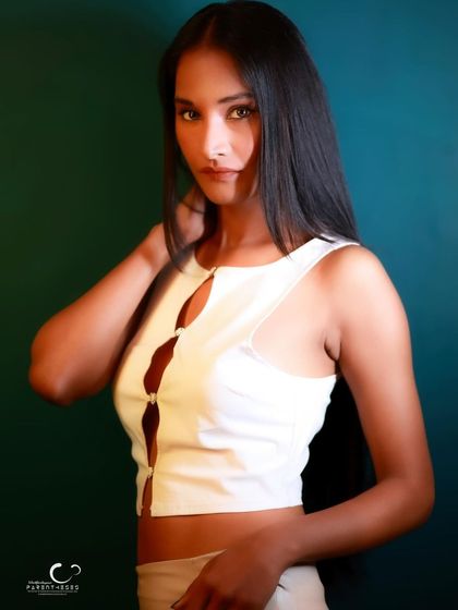 A confident and direct portrait against a dark green background. The simple styling and her strong gaze make for a powerful image.