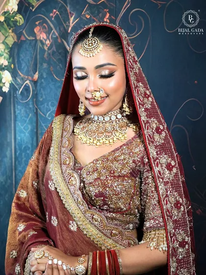 A beautiful bridal portrait with the dupatta veiled over her head. The metallic eyeshadow and gentle smile create a look of serene and timeless elegance, perfect for wedding photos.