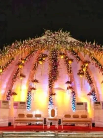 A magnificent dome-shaped stage structure for a grand reception, fully decorated with flowers and intricate lighting, creating a royal look.