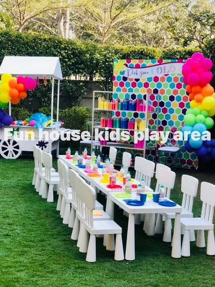 Our white tables and chairs set up as a vibrant art and craft station. The clean white furniture provides the perfect canvas for colorful activities, complete with a rainbow balloon garland and a cart full of supplies.