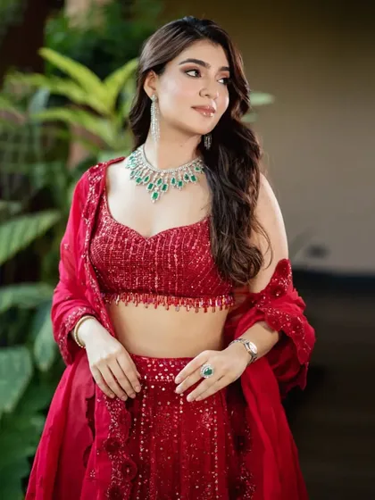 A beautiful portrait of the client in her red Sawan Gandhi lehenga, paired with a delicate diamond and emerald necklace.