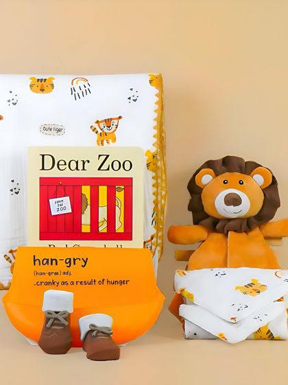 A jungle-themed baby gift set with a 'Dear Zoo' book and a lion toy. The warm, orange color palette and coordinated items make this a very appealing shot.