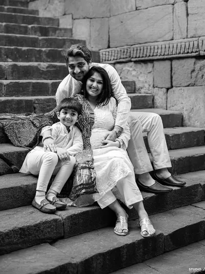 A classic family portrait on the steps. This black and white photo captures the love and connection of a family eagerly awaiting their new member.