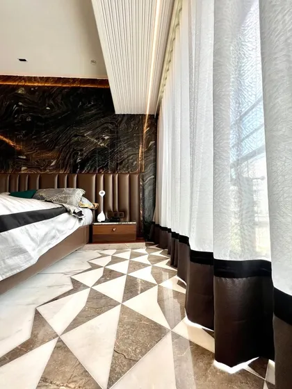 This bedroom proves you don't need a clutter of furniture to create a stunning space. The design is defined by the bold geometric marble flooring, a vertically fluted ceiling, and a dramatic dark marble feature wall.
