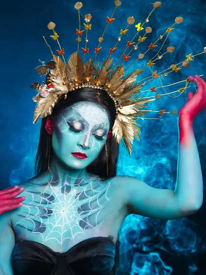 A full view of the fantasy look, showcasing the detailed spiderweb painting on the chest and the elaborate headgear.