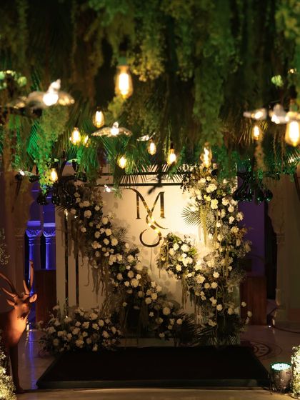 The photo-op spot, featuring the couple's monogram framed by white florals and foliage. This elegant installation was set against a backdrop of hanging greenery and warm lights, creating a perfect picture moment.