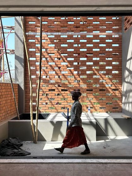 A worker walks past a newly constructed brick screen at our Alibaug site. The image captures the beautiful way sunlight filters through the perforations, turning a simple wall into an interactive surface.