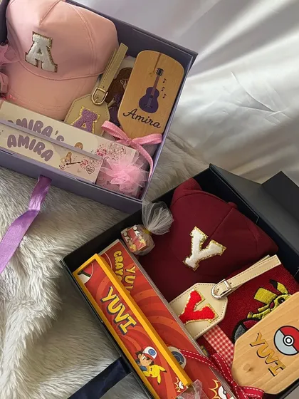 An overhead view of the two personalized stationery boxes, showing the different items like the custom caps and hairbrushes for each child.