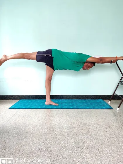 This is Veerabhadrasana 3 (Warrior 3 Pose) performed with the support of a chair. The chair allows you to hold the asana, focus on extending the spine and back leg, and build strength without compromising the alignment. This is how we make advanced postures accessible and safe for practice at home.