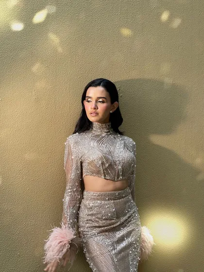 The full look against a textured wall. The hairstyle stands out and completes this high fashion ensemble.