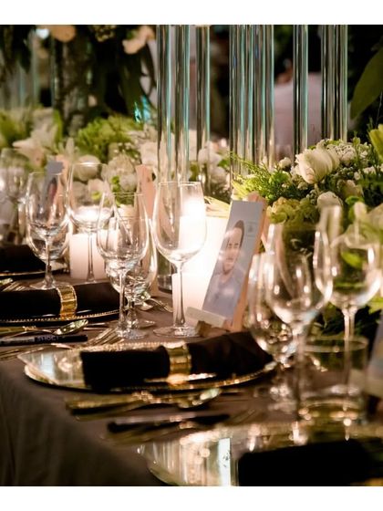A close up of a sophisticated table setting for a formal birthday dinner. The combination of classic white and gold dinnerware, crystal glassware, and soft candlelight reflects our attention to detail in creating a refined ambiance.