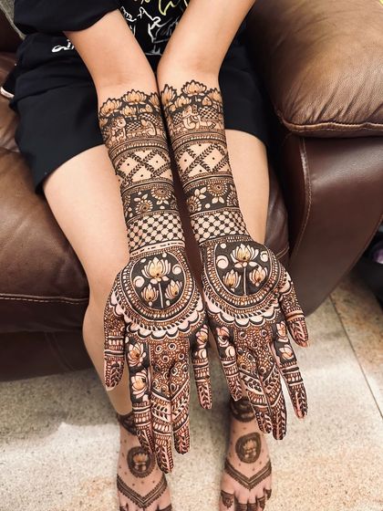 This design features large lotus mandalas on the palms, with checkerboard and floral bands on the arms.