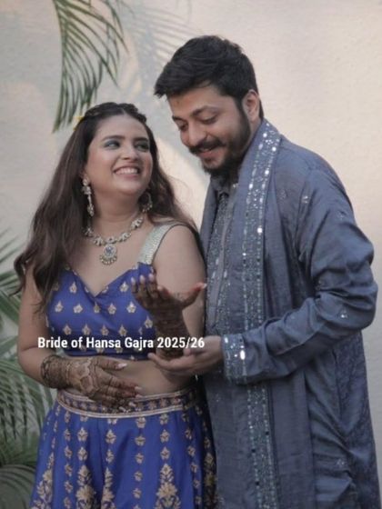 The groom admires the bride's mehendi, a classic and sweet moment from their celebration. Her smile shows her happiness with both the art and her partner's appreciation.