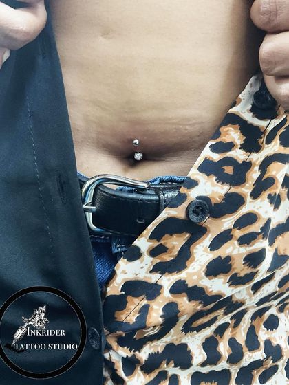 A stylish navel piercing shown with a fashionable outfit. This body modification is a great form of self-expression.
