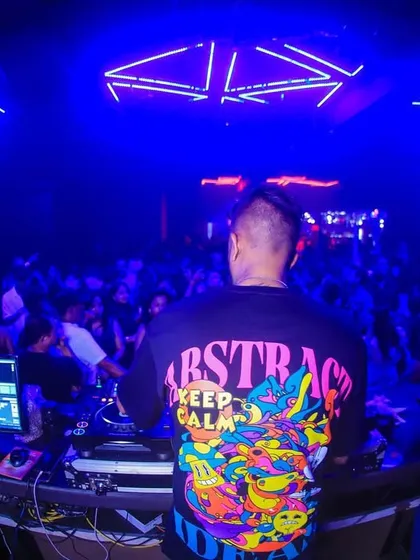 A view from behind the decks at Club Illusions, showing off my colorful t-shirt and the sea of people in front of me.