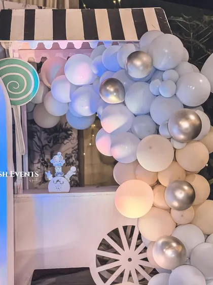 A detailed view of the candy cart at the pastel carnival, adorned with a beautiful balloon garland in shades of blue, white, and silver.