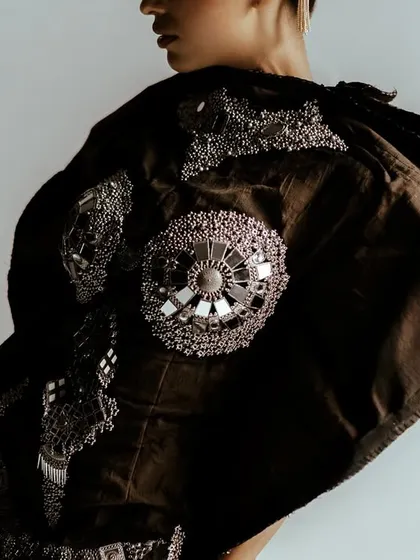 A profile shot focusing on the intricate mirror and thread work on a garment for Sheetal Zaveri. The movement in the fabric is captured to show its texture and flow.