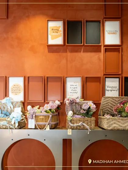 A view of the stylishly arranged gift baskets against a warm, textured wall in my Ahmedabad store. The framed quotes add a personal and inspiring touch to the decor.