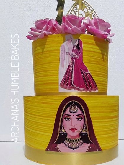 A vibrant yellow two-tiered wedding cake with traditional Indian bride and groom illustrations.