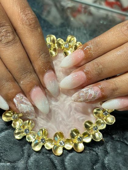 A soft white ombre set with accent nails featuring a delicate marble effect with hints of rose gold.