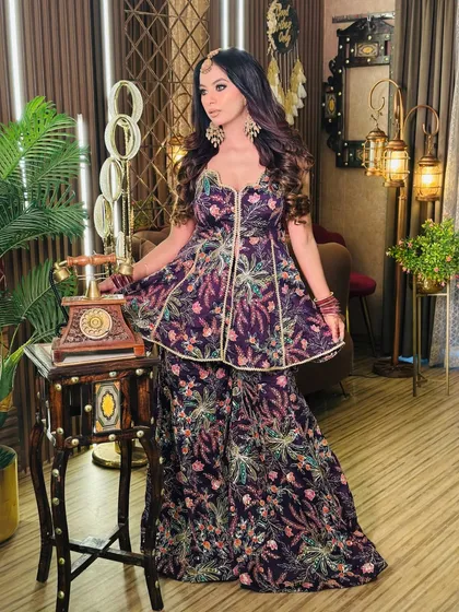 Go beyond the usual with my Indo-western collection. This deep purple peplum top and sharara set is perfect for a sangeet or mehendi, offering a modern twist on traditional wear with its intricate floral embroidery and flattering cut.