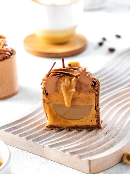 A cross-section of the hazelnut mousse dessert, revealing its luscious, multi-layered interior. This shot is designed to showcase the complexity and craftsmanship of the pastry, tempting customers with its hidden fillings.