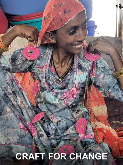 An artisan smiles as she displays earrings made from upcycled fabric scraps. Our Craft for Change initiative empowers artisans while reducing waste.