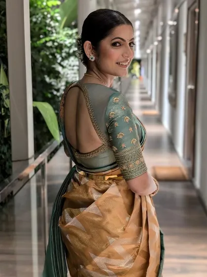 A graceful shot of a sage green blouse with a deep, rounded open back. The simple elegance of the cut is enhanced by delicate embroidery along the borders and sleeves.