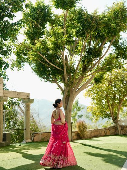A candid moment from a wedding shoot, showcasing a beautiful pink lehenga against a lush green background. This shows how I model in real event settings.
