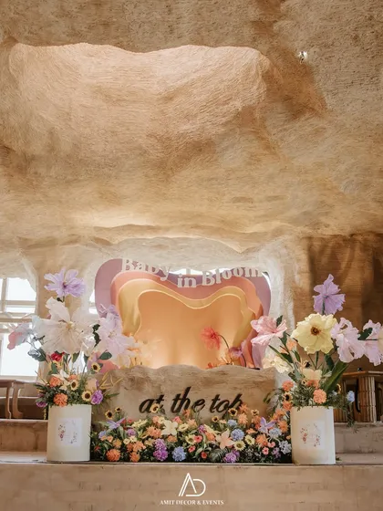 Let's bring your most whimsical ideas to life. This "Baby in Bloom" themed baby shower, set in a unique cave-like venue, features a custom heart-shaped backdrop and oversized paper flowers for a playful and unforgettable party.