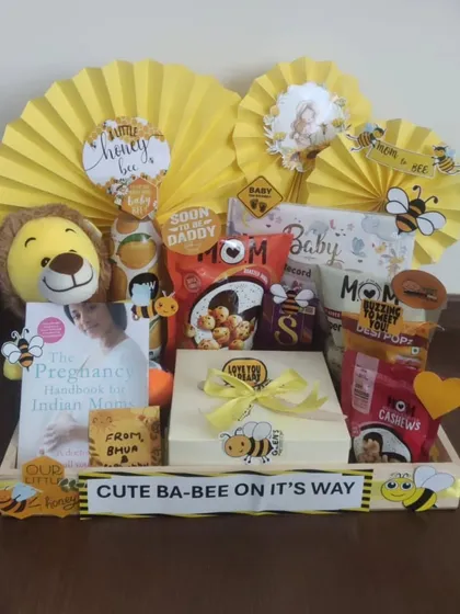 This 'Cute Ba-bee on its way' hamper is a sweet gift for expecting parents. It includes 'The Pregnancy Handbook for Indian Mothers', healthy snacks for the mom-to-be, and a cute lion plushie, all tied together with a cheerful yellow bee theme.