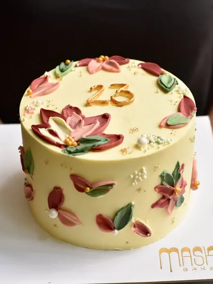 An elegant custom cake marking a 23rd birthday or anniversary, featuring beautifully piped lotus flowers and leaves in soft, artistic tones. This design shows how we can tailor our floral work to any occasion.