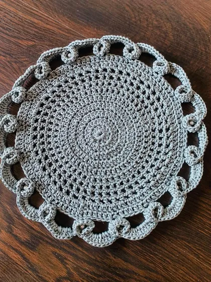 A top-down view of the grey lacy doily, showing the detailed stitch work and beautiful pattern.