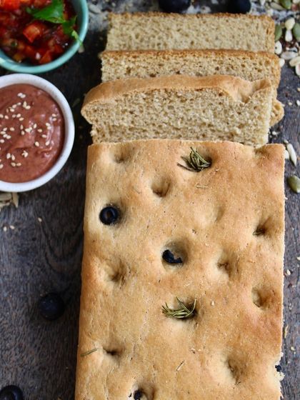 A loaf of our olive and rosemary focaccia, paired with fresh tomato salsa and bean hummus. It's a simple, rustic pleasure that's both healthy and delicious.
