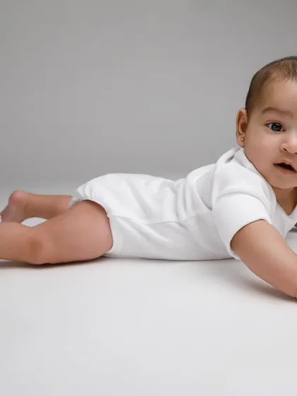Conquering tummy time like a champ. This simple, clean portrait on a grey background highlights the baby's strength and adorable expression.