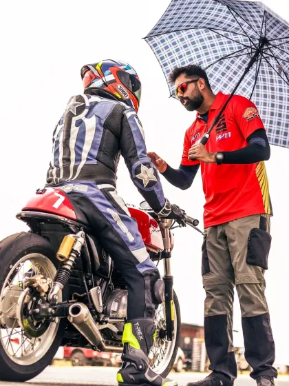 A coach provides guidance under an umbrella, showing our commitment to our riders, rain or shine. We're dedicated to helping you improve, no matter the conditions.