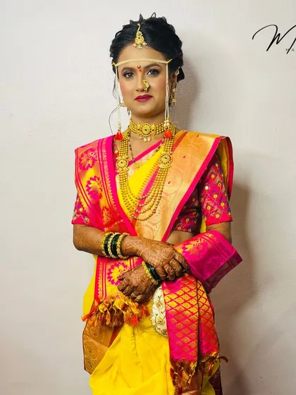 This bride in her yellow and pink Nauvari saree looks absolutely radiant. The look is completed with the traditional mundavalya headpiece, signifying she is ready for the wedding rituals.
