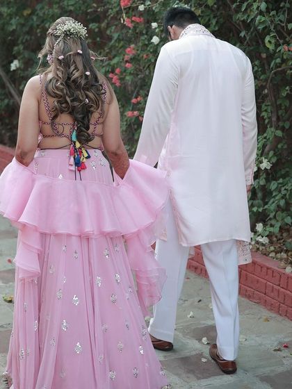 A candid moment from a dreamy Mehendi ceremony. The bride's backless blouse and unique hairstyle are the stars of this shot.
