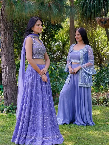 A full-length shot of two models in a garden setting, showcasing their coordinated lavender outfits. This image effectively displays how different styles from the same collection can be worn together.