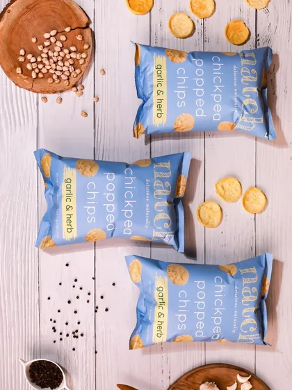 A rustic flatlay for garlic & herb chips on a white wooden background. This styling gives a natural and wholesome feel to the product.
