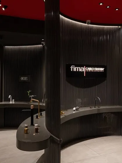 The interior of the FIMA store, where products are displayed like art in a museum. The curved counters and dark, slatted walls create distinct zones, allowing customers to explore different collections in a thoughtfully designed sequence.