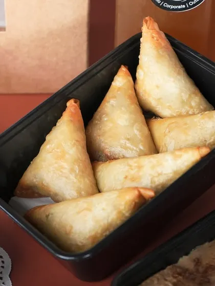 A container full of my popular Chicken and Cheese Samosas, a classic snack that's perfect for any gathering.