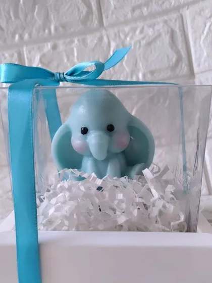 A cute baby elephant candle in blue, packaged in a clear box with a matching ribbon. A wonderful favor for celebrating the arrival of a baby boy.
