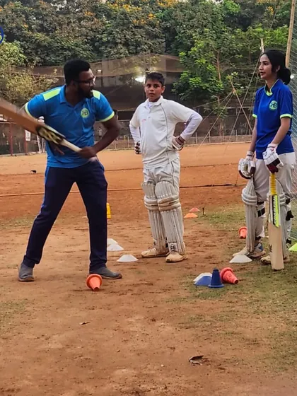 Personal attention is key to development. Here, a coach provides one-on-one batting stance correction to young male and female cricketers, ensuring they build a strong technical foundation from the start.