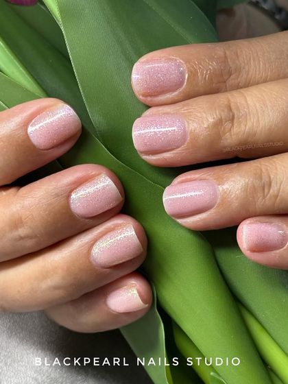 A beautiful example of BIAB nails with a stunning glitter topcoat. This technique provides a flawless, chip-free finish that strengthens weak nails and adds a touch of subtle shimmer.