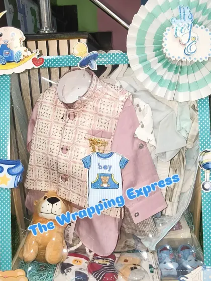 A welcome hamper for a baby boy, featuring a traditional kurta set, a soft toy, and other baby necessities, all arranged in a mint green and blue themed basket.