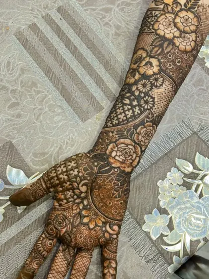 A complete back-of-hand bridal design extending up the forearm. This piece features beautiful rose motifs combined with geometric grids and leafy patterns for a balanced look.